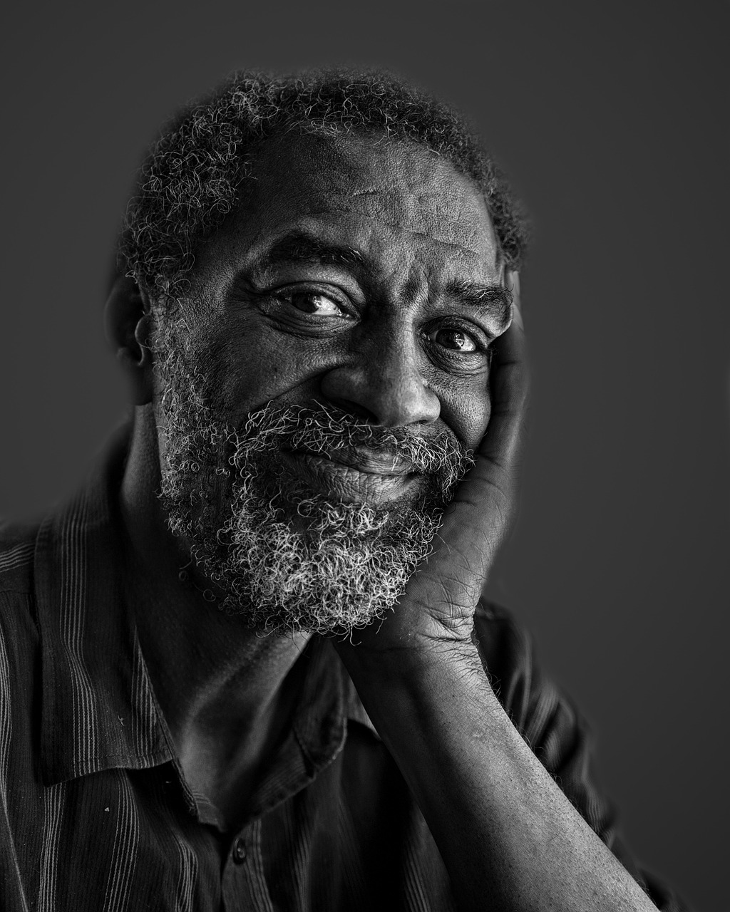 Wisdom with dignity An older black man leaning on his hand with a gentle smile.